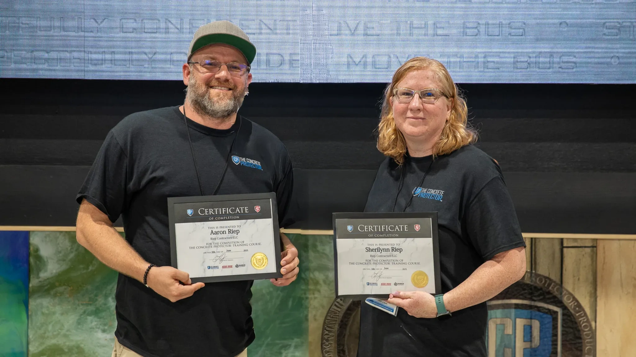 Owners of Eminence Concrete Coatings, Sherilynn and Aaron Riep, holding certificates of completion.